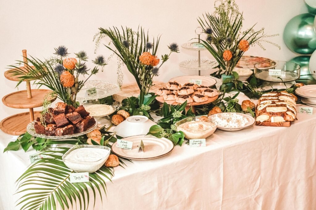 An elegant buffet table adorned with desserts, greenery, and floral arrangements in a Paris setting.