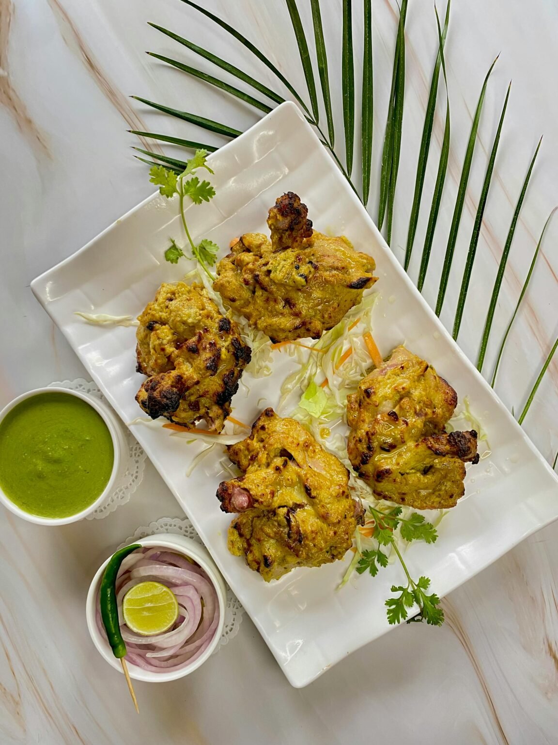 Overhead shot of flavorful Indian tandoori chicken with accompaniments, perfect for food lovers.
