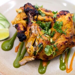 Delicious spicy grilled chicken garnished with cilantro and lime, perfect for a tasty meal.