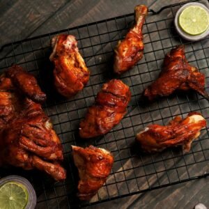 Tasty grilled chicken pieces on a wire rack with onion and lime garnishes.