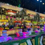 Grand outdoor wedding fruit buffet counter with gold mirror panels colourful lighting and fresh fruit display at night
