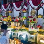 : Decorated outdoor wedding catering buffet counter with floral arrangements iron cage decor and warm lighting at night